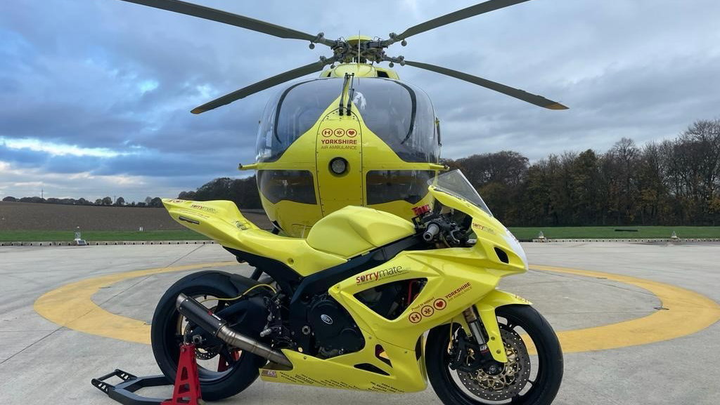 Photo of yellow motorcycle in front of yellow helicopter